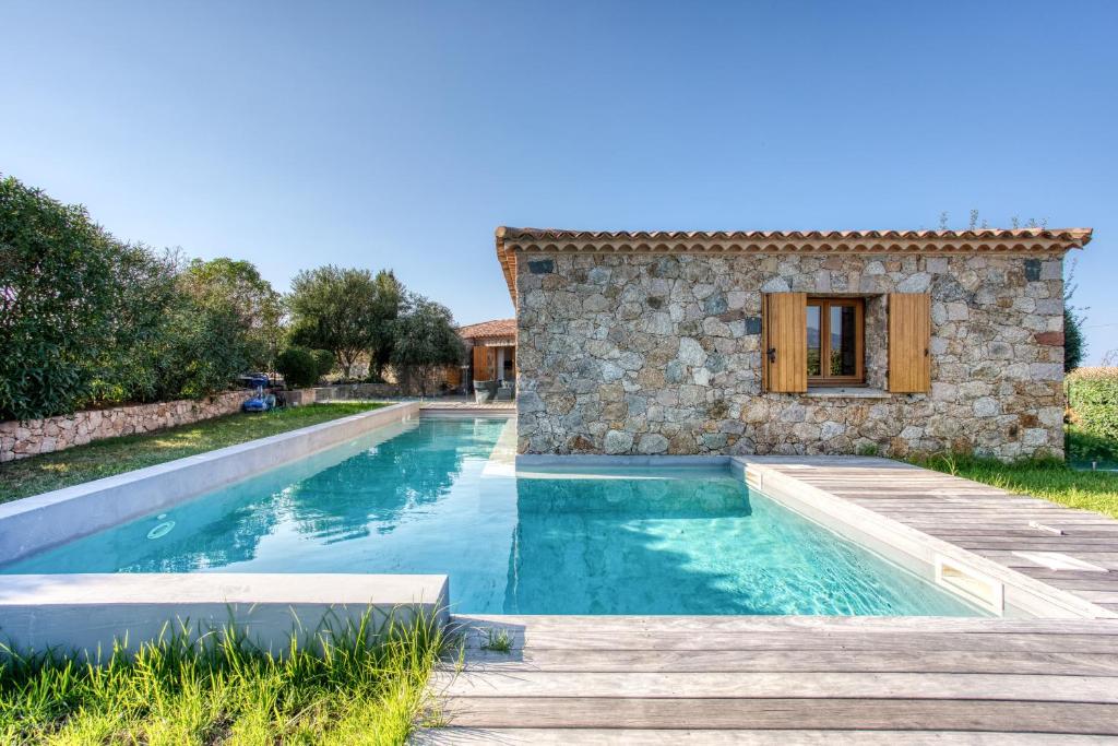 una piscina frente a una casa de piedra en Villa Stella, en Lumio