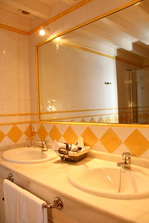 a bathroom with two sinks and a large mirror at Hotel Tugasa Castillo de Castellar in Castellar de la Frontera