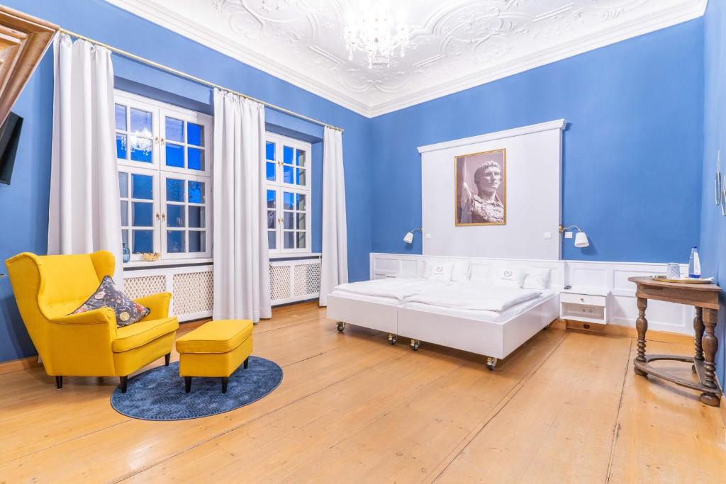 a blue bedroom with a bed and a yellow chair at Gasthof Römischer Kaiser in Ellingen