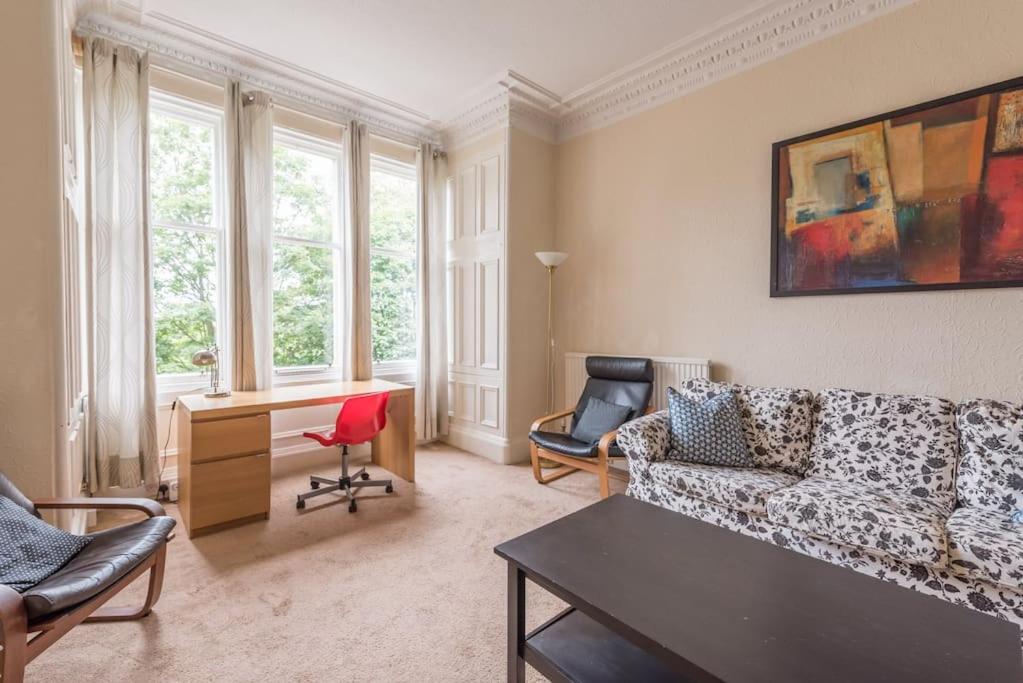 - un salon avec un canapé, un bureau et des fenêtres dans l'établissement Beautiful 2 Bed 2 Bath Flat overlooking Meadows Park, à Édimbourg