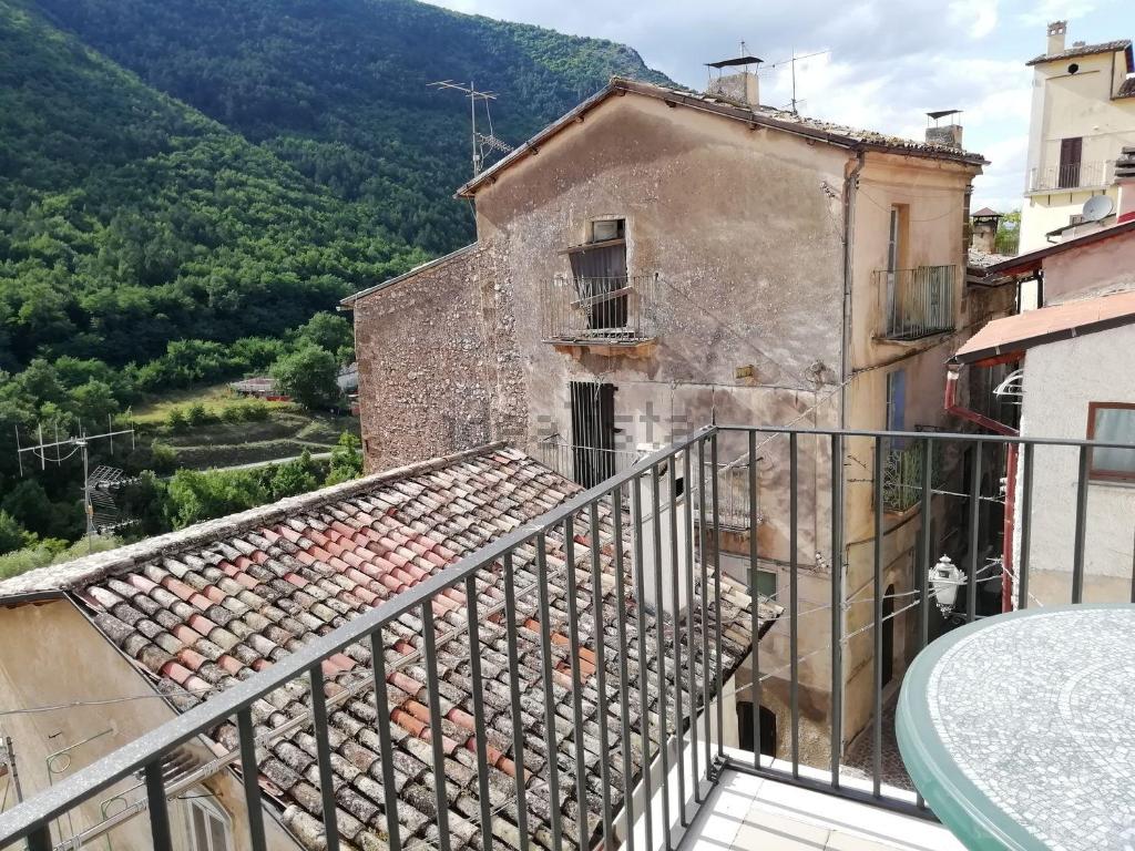 un balcón de un edificio antiguo con montañas en el fondo en Casa nel borgo nella natura en Pettorano sul Gizio