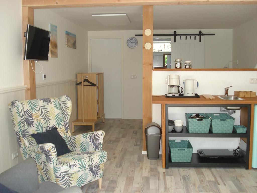 a living room with a chair and a table at Strandstudio Cato, vlakbij zee! in Callantsoog