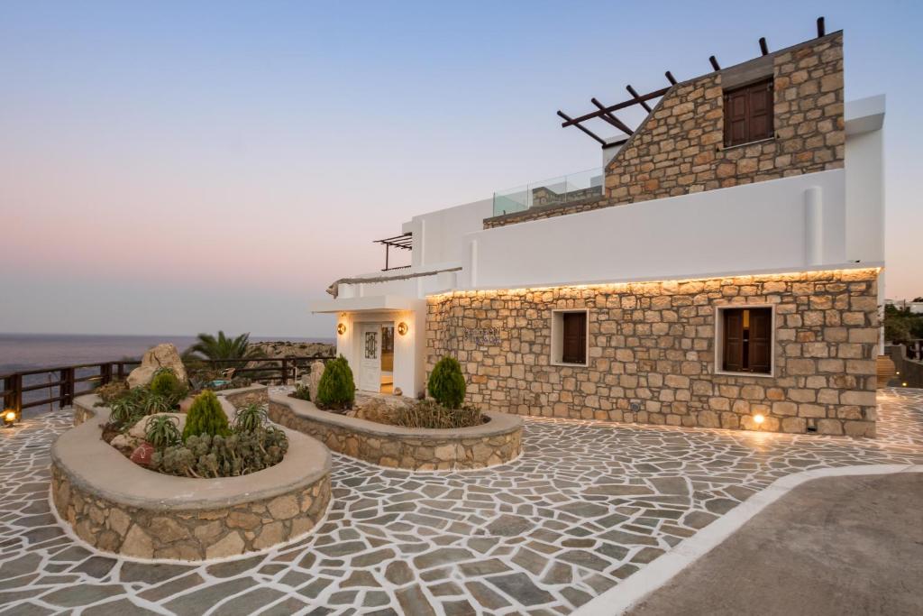 a building with a stone walkway next to the ocean at Aegean Village Beachfront Resort in Amoopi