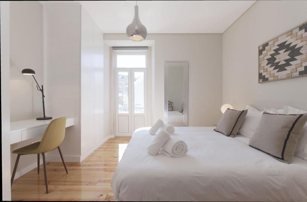 a white bedroom with a white bed and a chair at Apartamento Andrade in Lisbon