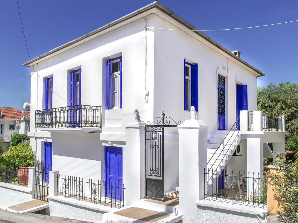 a white house with blue doors and a gate at Anticlea I in Vathi