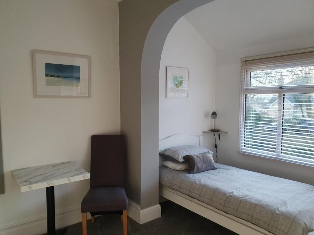 een slaapkamer met een bed, een bureau en een raam bij Chynoweth Lodge in Newquay