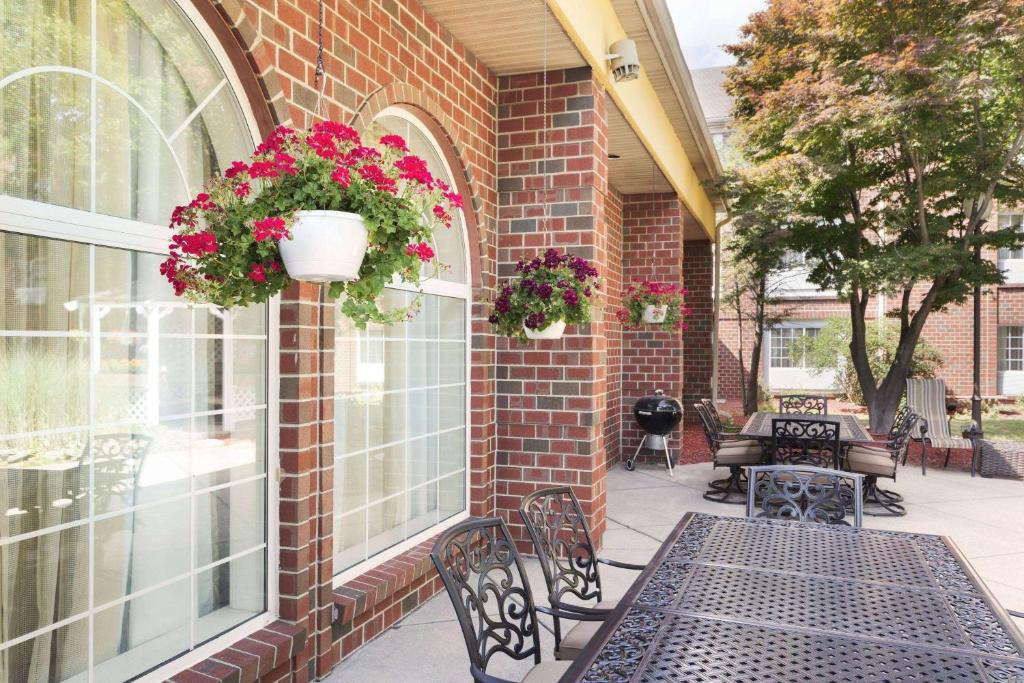 - un patio avec des bancs et des fleurs dans un bâtiment en briques dans l'établissement Wyndham Garden Grand Rapids Airport, à Grand Rapids