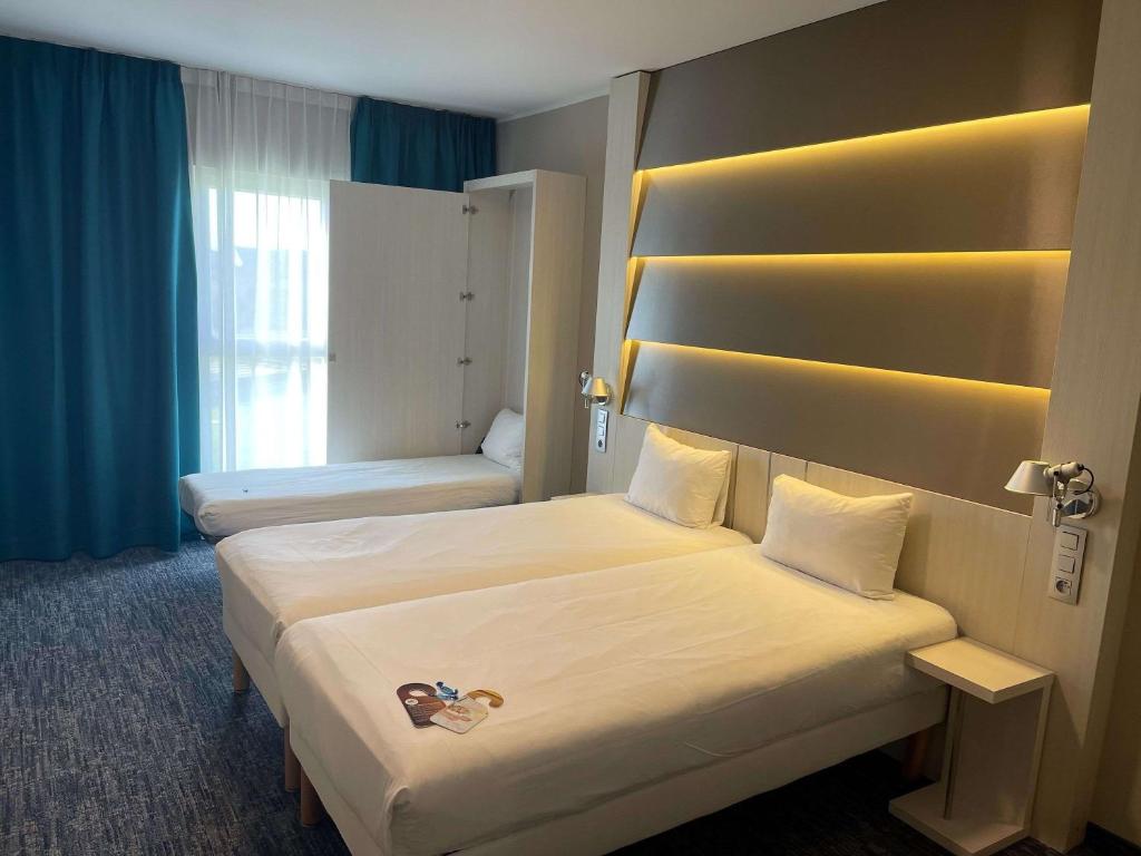 a hotel room with two beds and a window at ibis Styles Nivelles in Nivelles