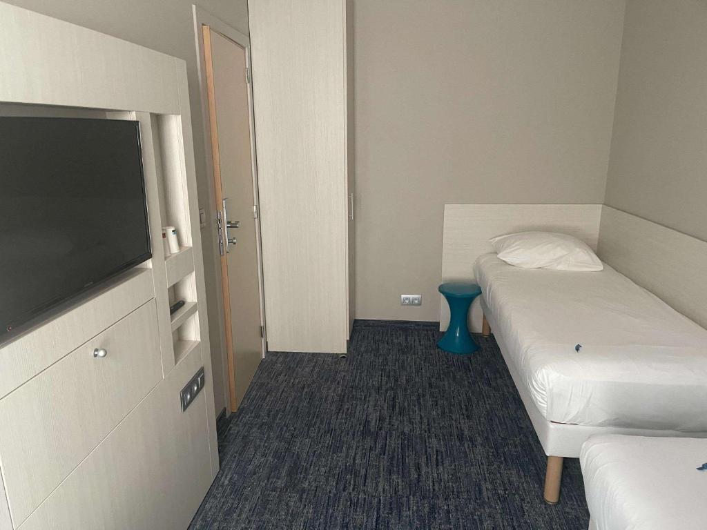 a hotel room with two beds and a flat screen tv at ibis Styles Nivelles in Nivelles