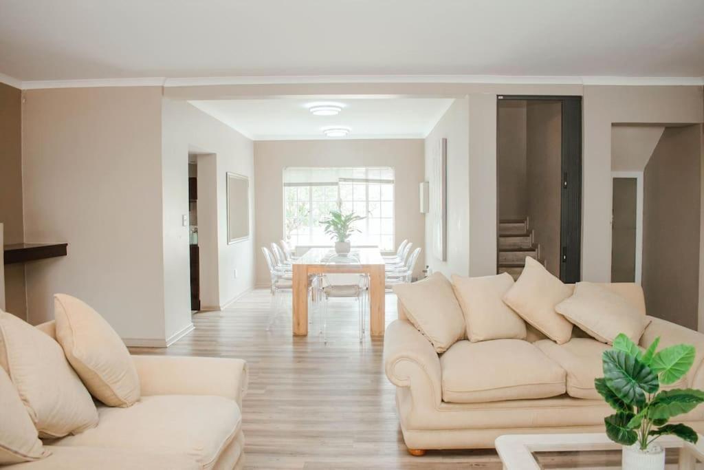 Private luxurious 3 bedroom complete house في بلومفونتين: غرفة معيشة مع كنبتين بيضاء وطاولة