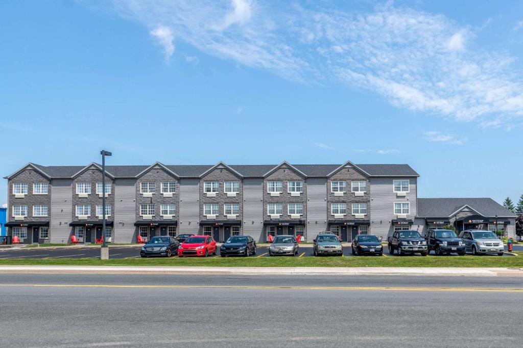 un gran edificio con coches estacionados en un estacionamiento en Quality Inn Amsterdam Fredericton, en Fredericton