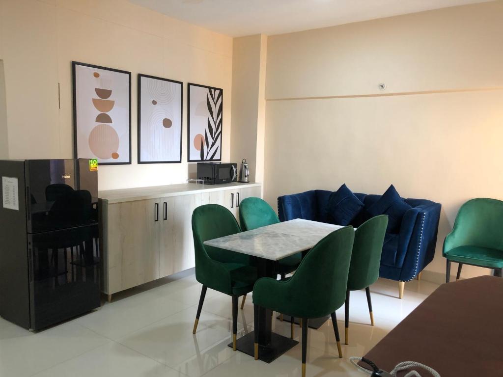 une salle à manger avec une table et des chaises vertes dans l'établissement Hamsun Apart Hotel Clifton, à Karachi