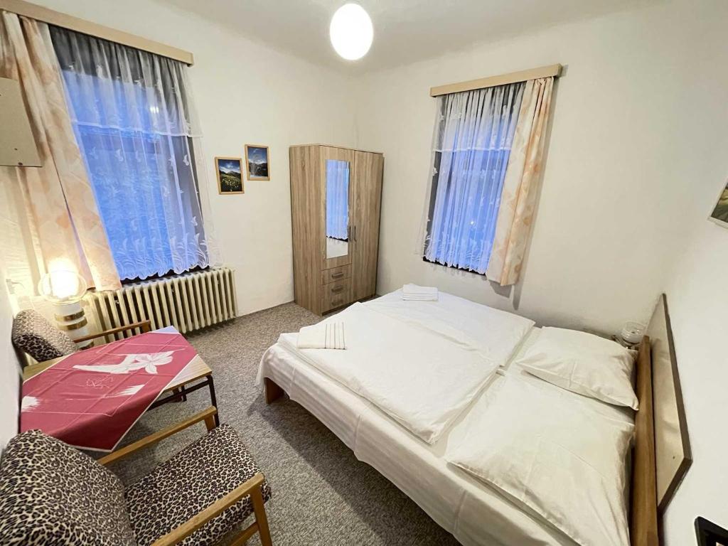 a bedroom with a bed and a chair and two windows at Zlatá vyhlídka in Benecko