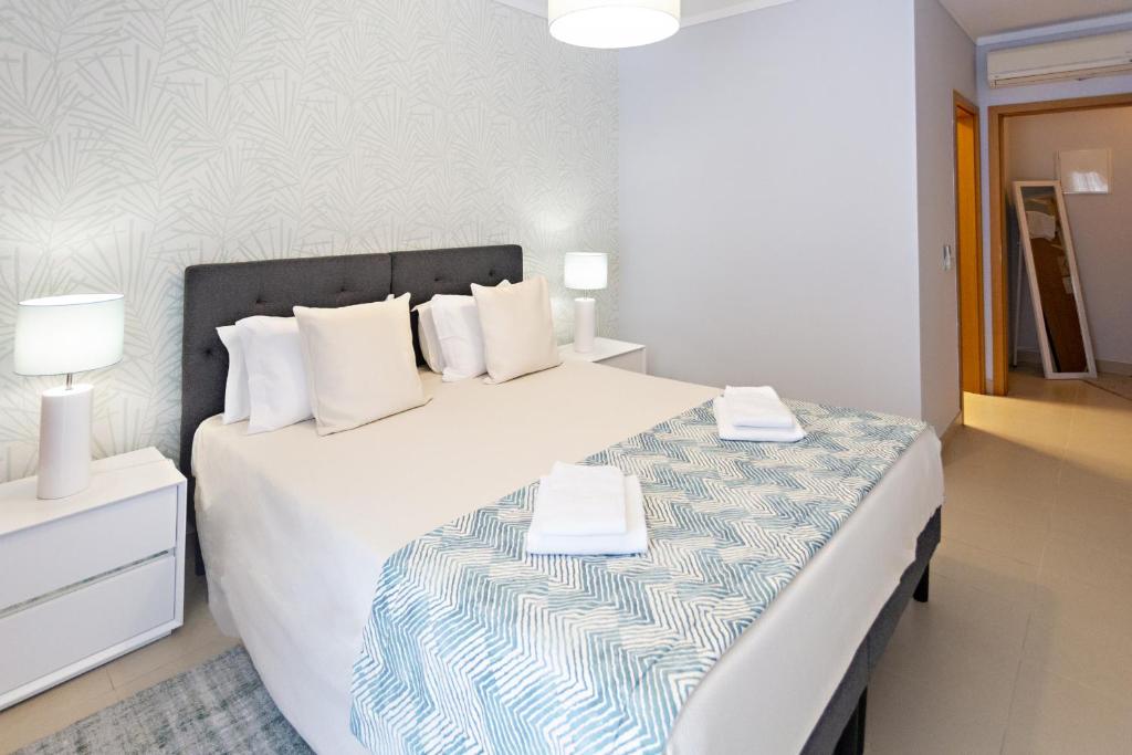 1 dormitorio con 1 cama grande con sábanas y almohadas blancas en Fisherman 21 - Cabanas Beach en Cabanas de Tavira