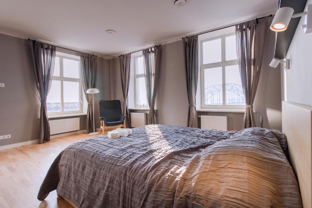 um quarto com uma cama grande e 2 janelas em Modern apartment in Old Riga with a river view em Riga