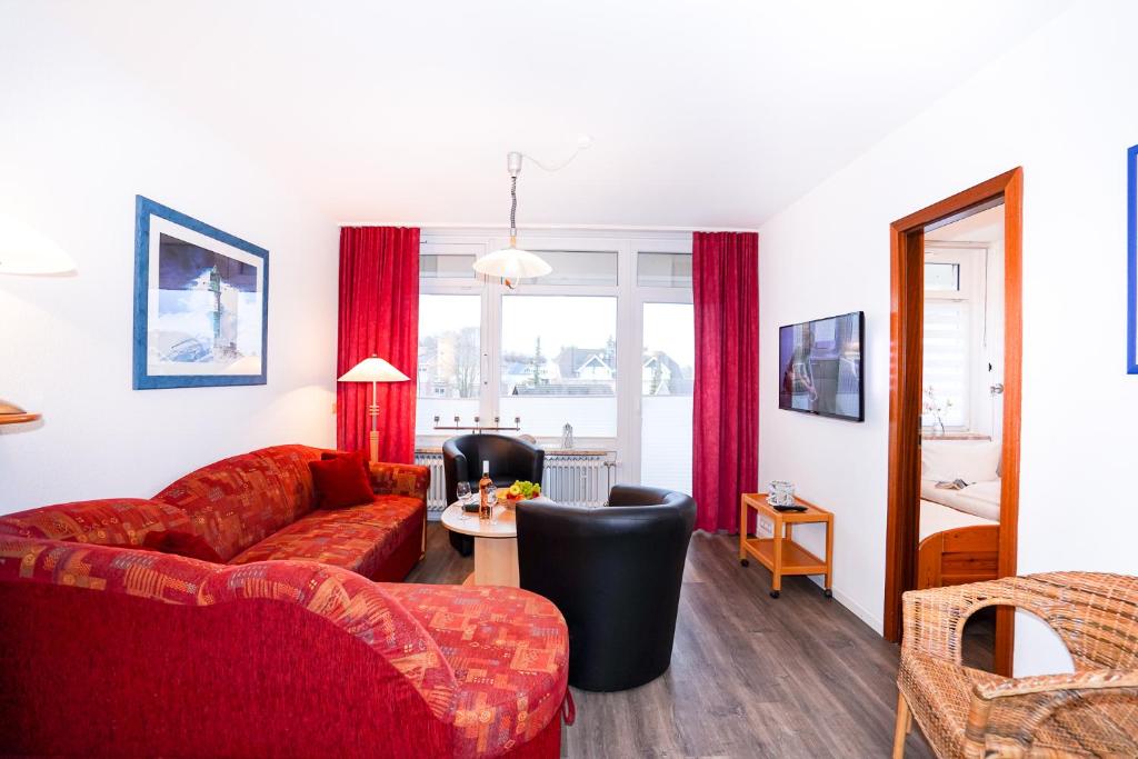 un soggiorno con divano rosso e tavolo di Marina45, Grömitz a Grömitz