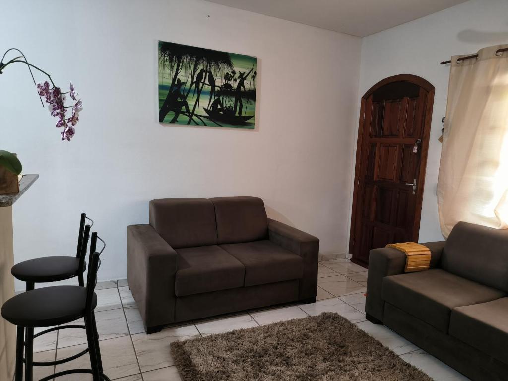 een woonkamer met een bank en een stoel bij Casa em Condomínio Martin de Sa in Caraguatatuba