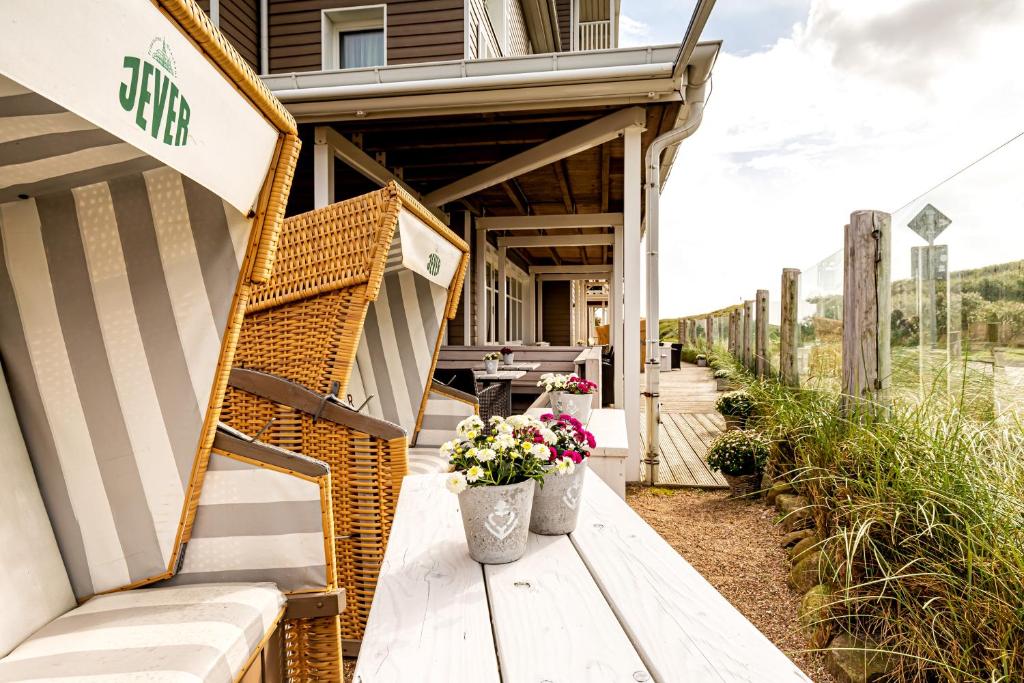 a porch of a house with a wicker bench and flowers at Hotel Zweite Heimat in Sankt Peter-Ording