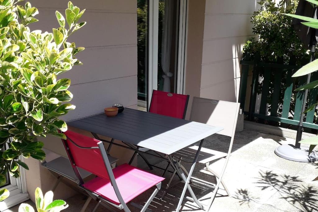 einen schwarzen Tisch und zwei rote Stühle auf einer Veranda in der Unterkunft Arcachon T2 Calme proche plages et commerces et 2 vélos in Arcachon