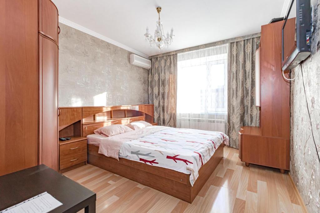 a bedroom with a bed and a large window at Уютная квартира in Astana
