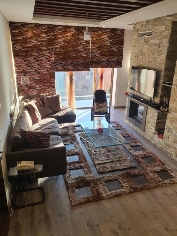 ein Wohnzimmer mit einem Sofa und einem Kamin in der Unterkunft LES Dunes De Faqra ( c duplex ) in Abū Mīzān
