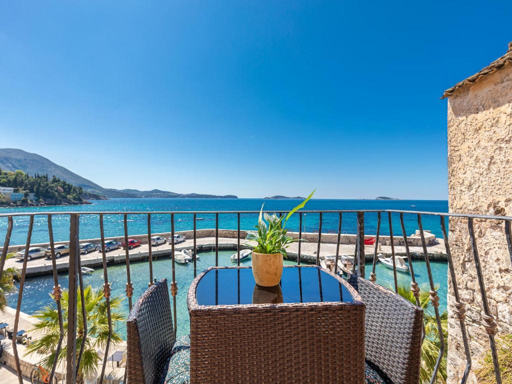 Villa Ana Apartments في مْليني: طاولة مع نبات الفخار على شرفة تطل على المحيط
