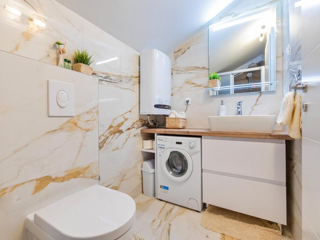 a bathroom with a toilet sink and a washing machine at Villa Ana Apartments in Mlini