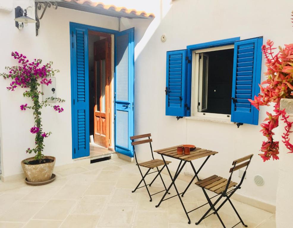 un patio con persiane blu, tavolo e sedie di Casa Chicca Salentro a Botrugno