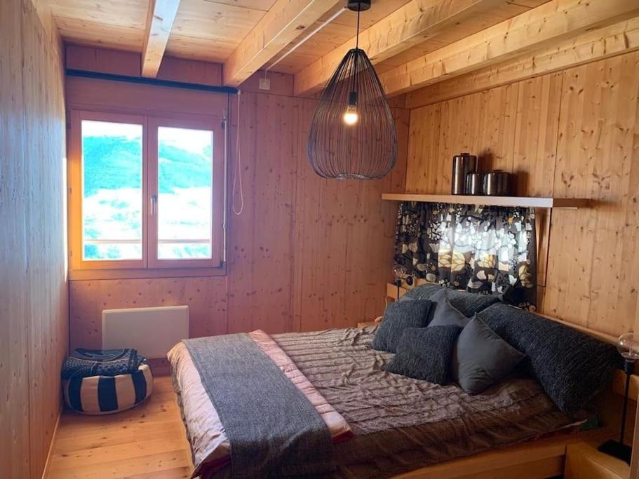 1 dormitorio con 1 cama en una pared de madera en Chalet , Thyon Les Collons, 4 Vallées, en Les Collons