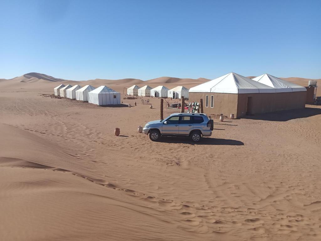 Un todoterreno estacionado en el desierto con tiendas de campaña en Couleur du désert en Mhamid