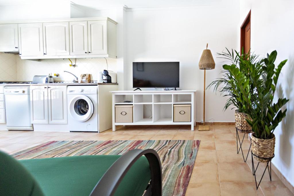 a kitchen with white cabinets and a washer and dryer at Cabanas Vintage Apartment in Tavira