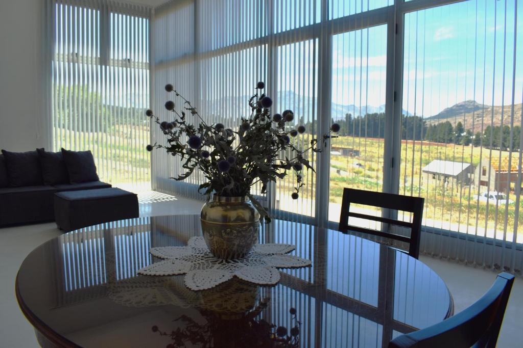 une table en verre avec un vase et des fleurs sur lui dans l'établissement Las Loicas B&B, à Esquel