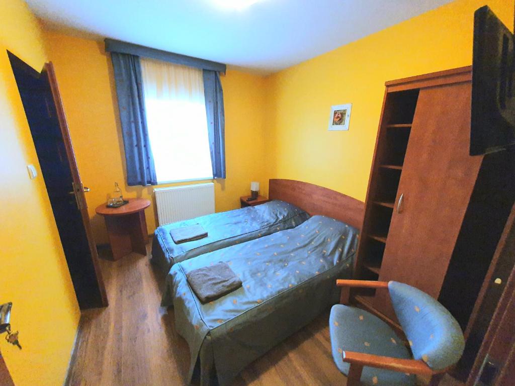 a small bedroom with a bed and a chair at Chata Zieleniecka in Duszniki Zdrój