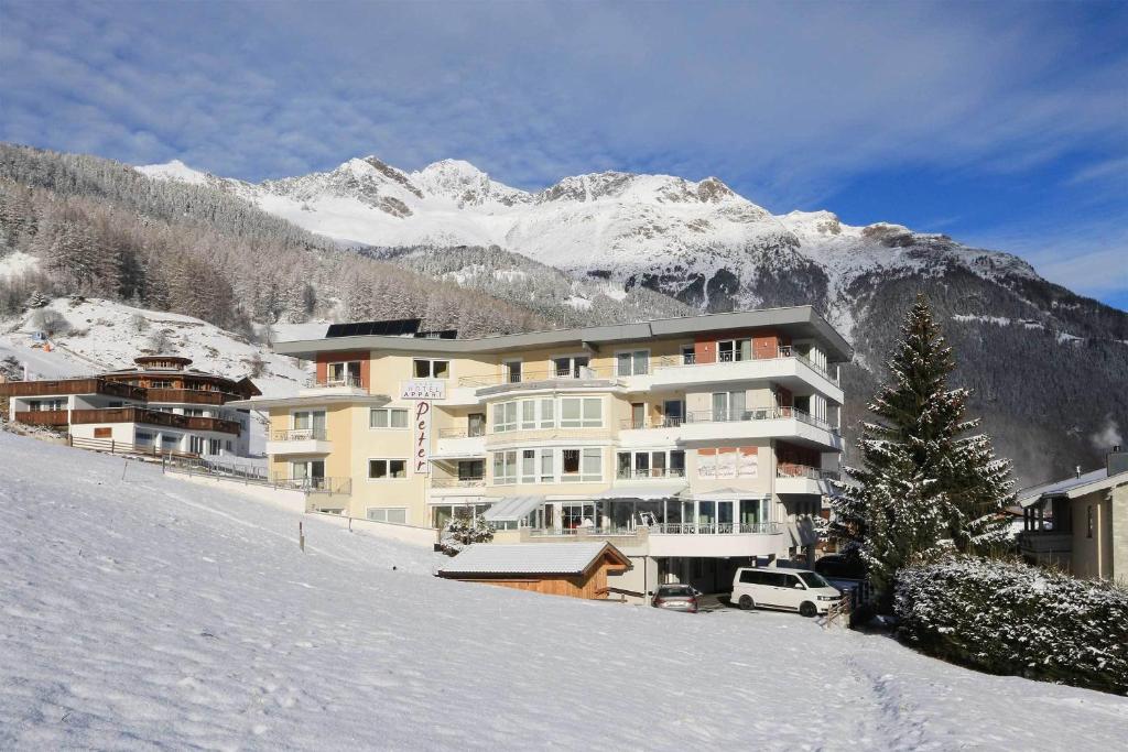 a large building in the snow in front of a mountain at Hotel Appart Peter in Sölden