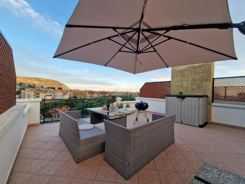 a patio with a table and chairs and an umbrella at 650 metri dal Mare - WiFi - Terrazzo - Piscina - A/C in Pietra Ligure