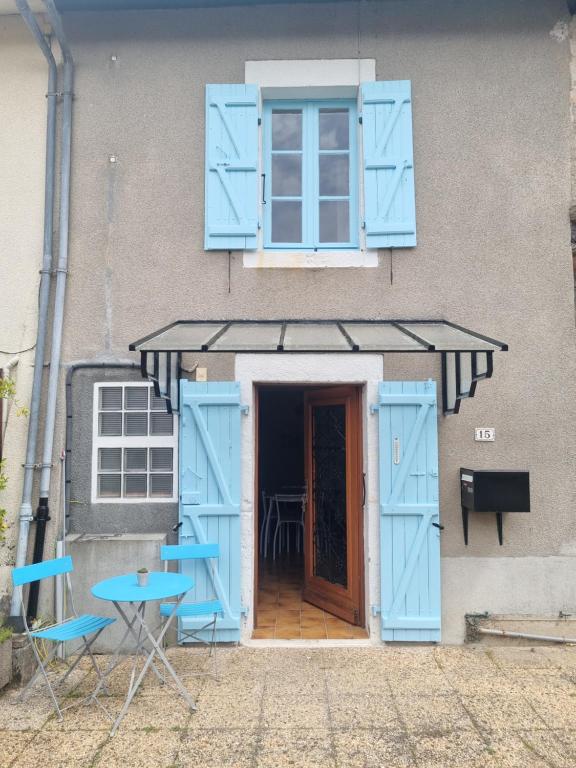 a building with blue doors and a table and chairs at Jolie petite maison dans village fortifié in Brigueuil