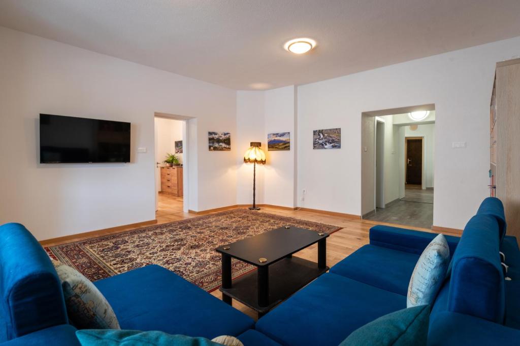 a living room with a blue couch and a table at Apartmán LM - moderný a veľký 90m2 - v centre mesta in Liptovský Mikuláš