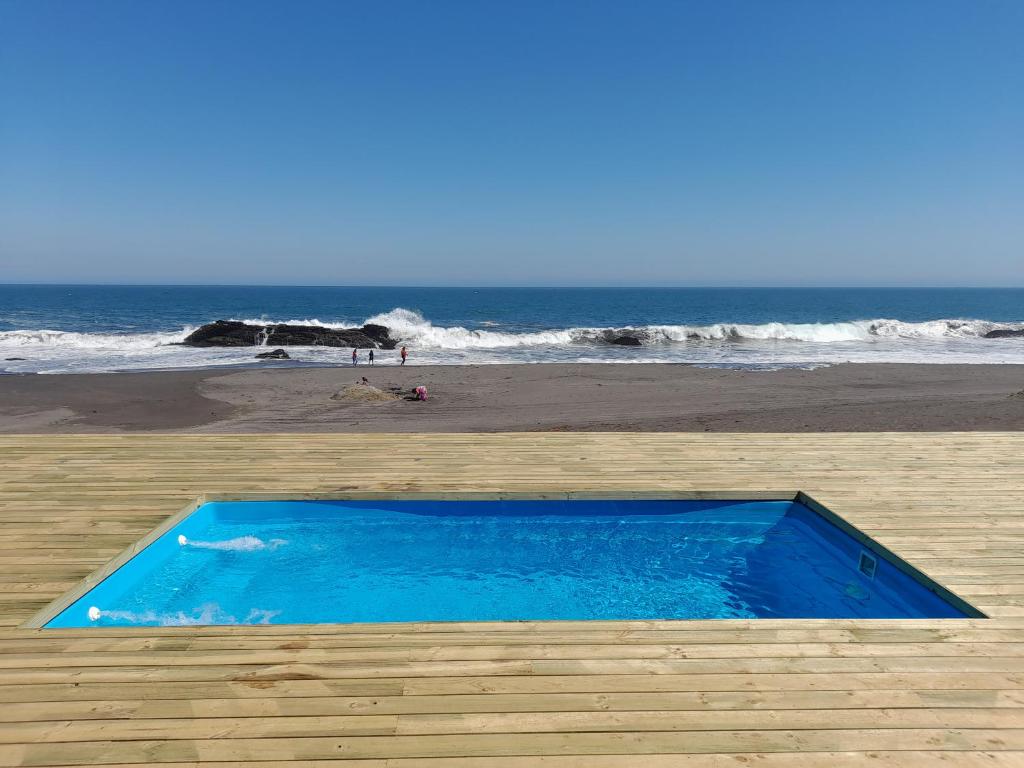 una piscina blu su una spiaggia vicino all'oceano di Casa MORENA by Alto Curanipe a Pelluhue
