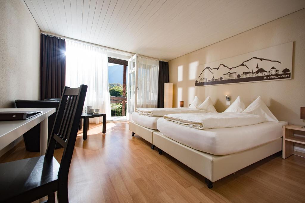 Habitación de hotel con 2 camas, escritorio y escritorio. en Jungfrau Hotel Annex Alpine-Inn, en Wilderswil