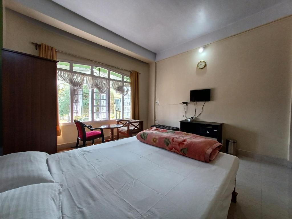 een slaapkamer met een groot wit bed en een tafel bij Odyssey Stays Jowai - West Jaintia Hills in Jowai