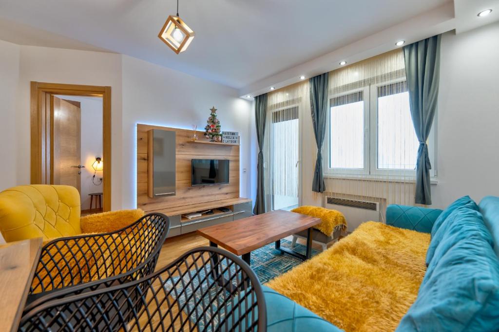 Una sala de estar con un sofá azul y una mesa. en Apartman Relja Zlatibor, en Zlatibor