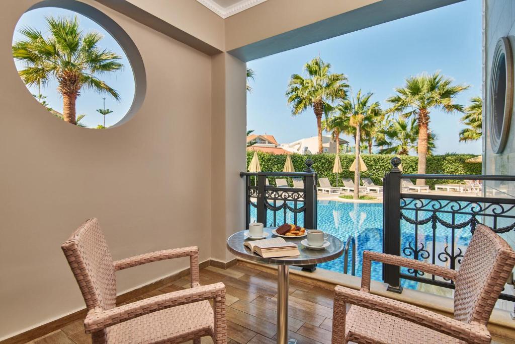 een terras met een tafel en stoelen en een zwembad bij Palazetto Suites Zakynthos - Adults Only in Tsilivi