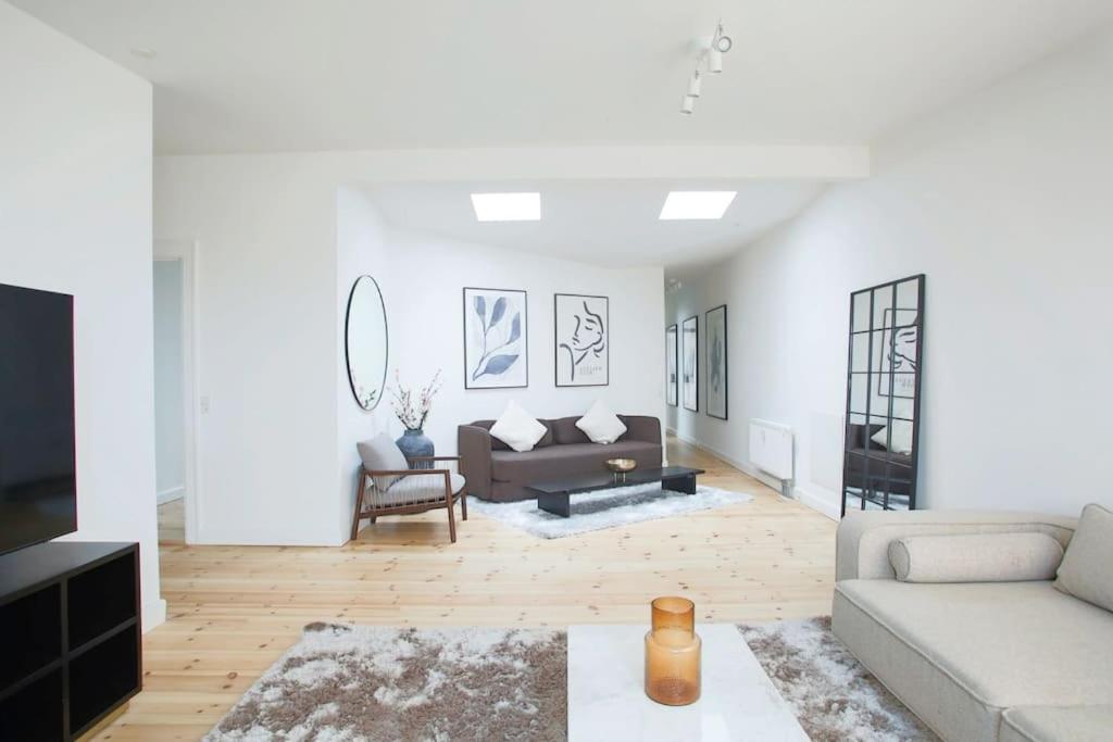uma sala de estar com paredes brancas e um sofá em Cozy 3BR Lake View Flat w Bath Tub in Copenhagen em Copenhague