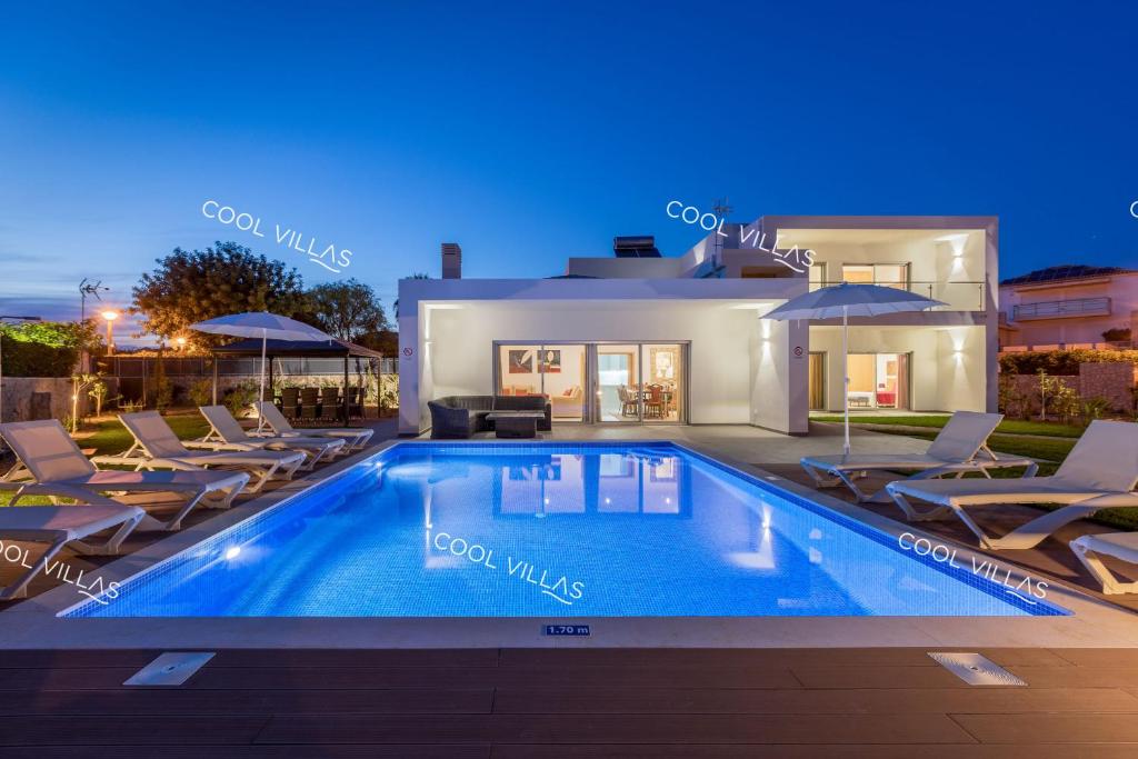 a villa with a swimming pool in front of a house at Villa Alfazema - heatable pool in Albufeira