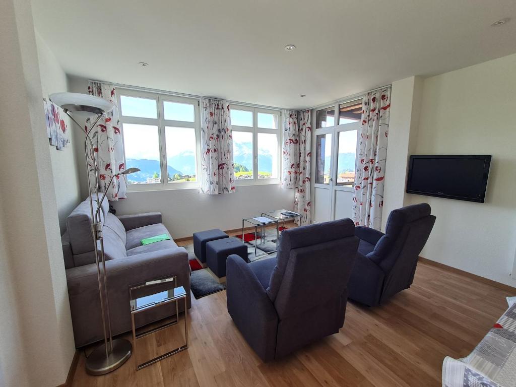 a living room with a couch and chairs and a television at Appartement au centre du village 4-6 personnes in Leysin