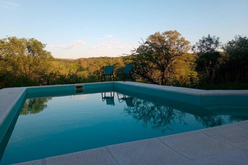 una piscina con 2 sillas junto a ella en Finca El Pacará en Agua de Oro