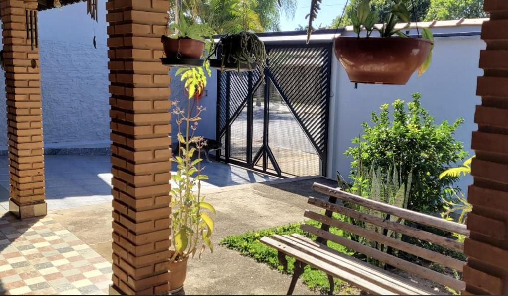 um banco de madeira ao lado de um portão com plantas em CASA AZUL São Pedro em São Pedro