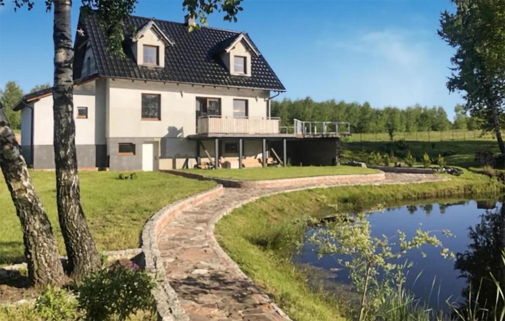 a house with a pond in front of it at Cozy Home In Grabowska Huta With Outdoor Swimming Pool in Nowa Karczma