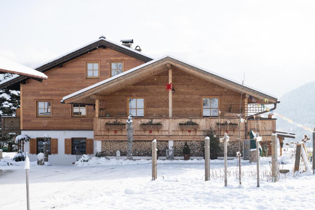 un grand bâtiment en bois avec de la neige devant lui dans l'établissement Ferienwohnungen Mooshäusl, à Reit im Winkl