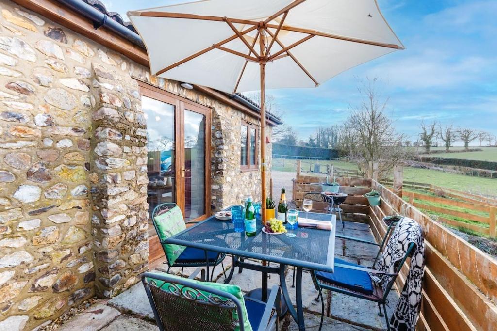 einen Tisch und Stühle mit Sonnenschirm auf einer Terrasse in der Unterkunft The Croft @ Warrens Farm in Taunton
